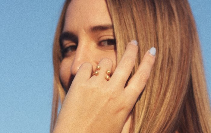 Mujer llevando un anillo dorado artesanal minimalista de Ingràvita Joyas durante la puesta de sol.